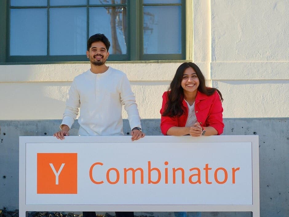 Deploy founders Sahith Chada and Irene Grace Karot Polson beside the Y Combinator sign